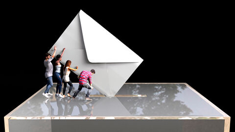 Vier Personen die einen übergroßen Wahlbrief in eine Wahlurne werfen.